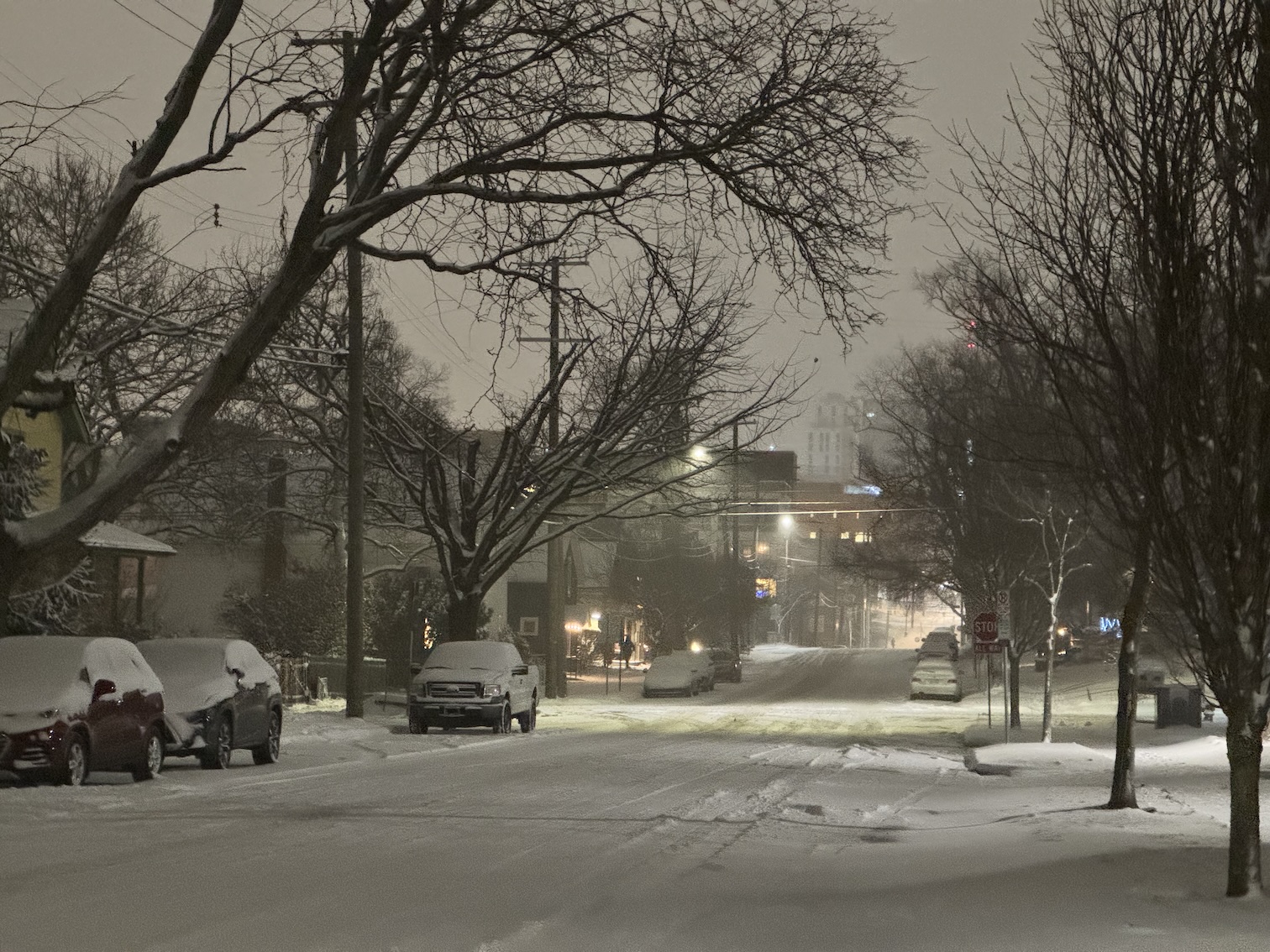 An Ann Arbor neighborhood street at night completely covered by heavy, unplowed snow.