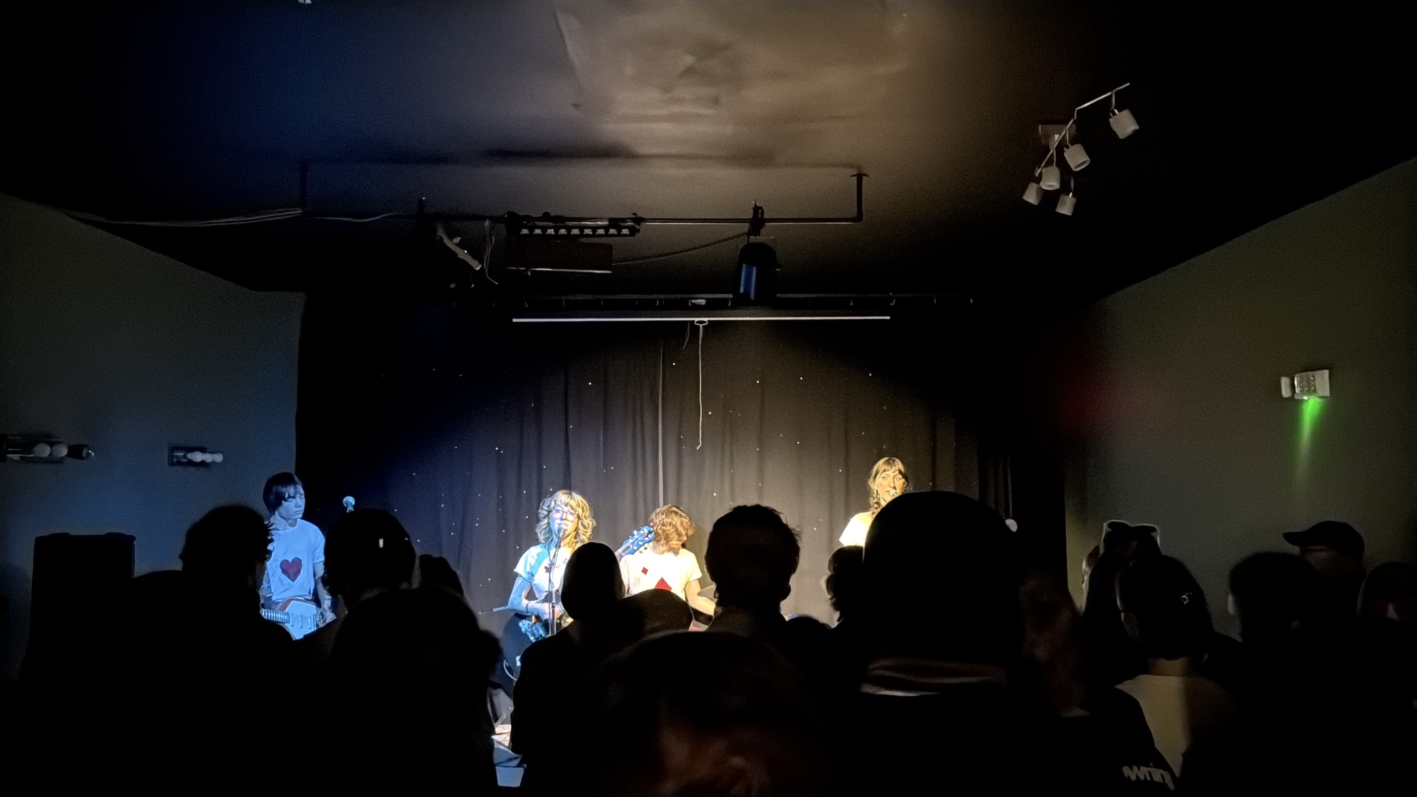 An indie band performs on stage in a small local venue.