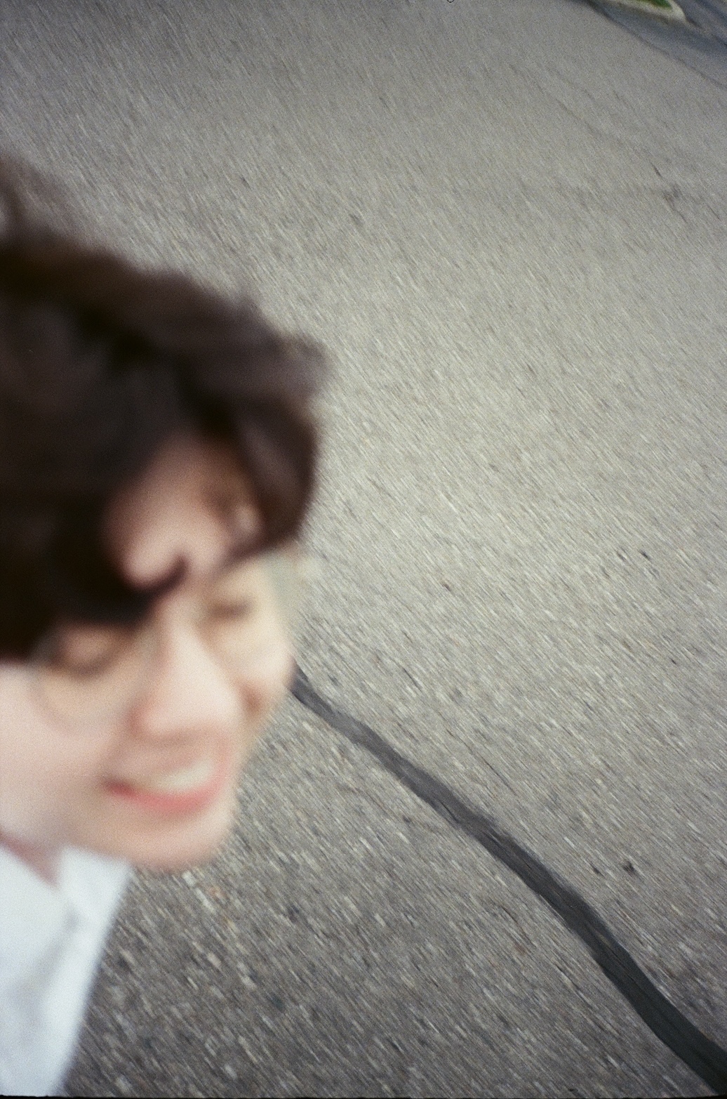 An out-of-focus selfie of myself smiling and walking down the sidewalk.