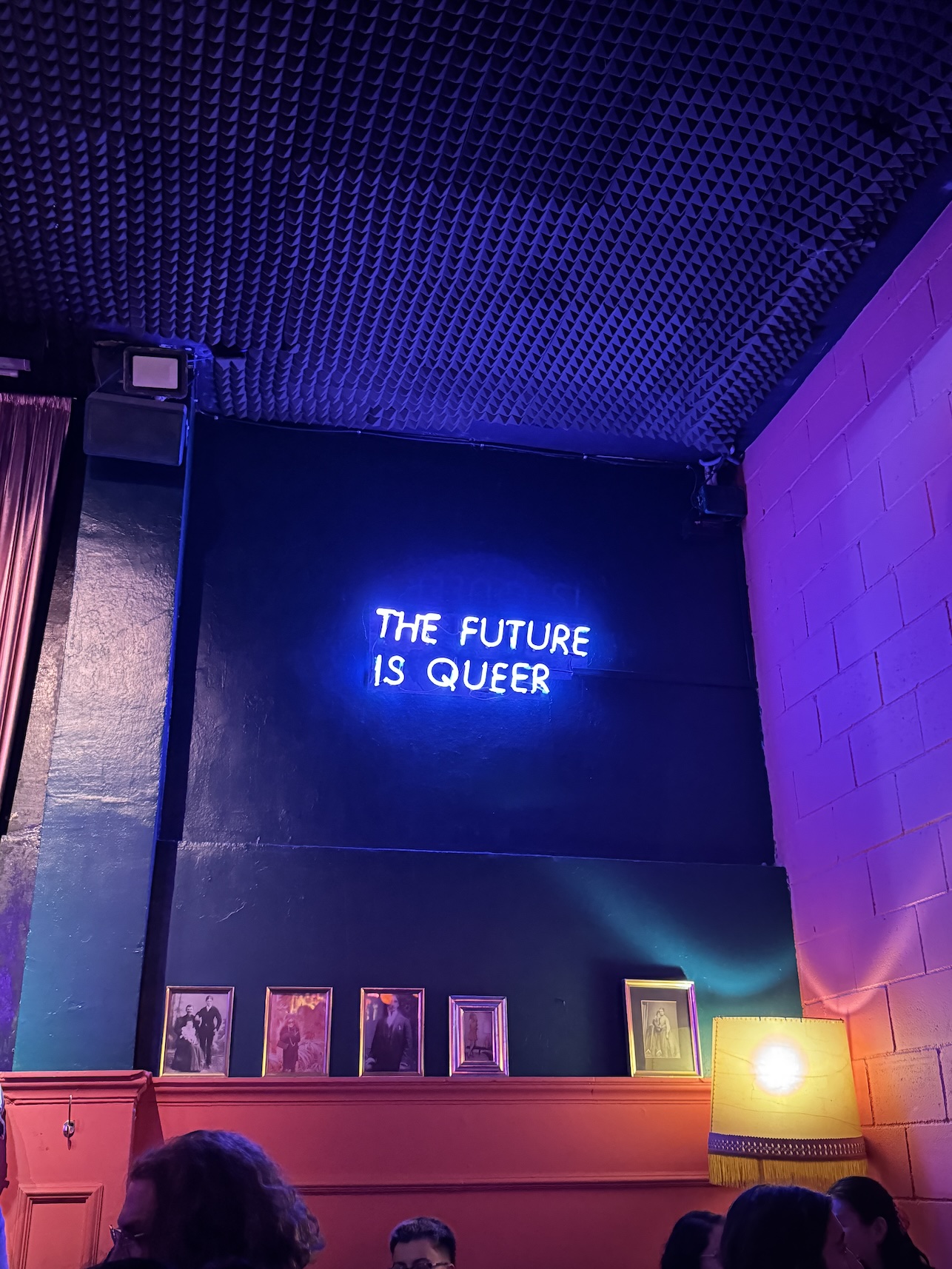 A neon sign inside a queer bar that reads, THE FUTURE IS QUEER.