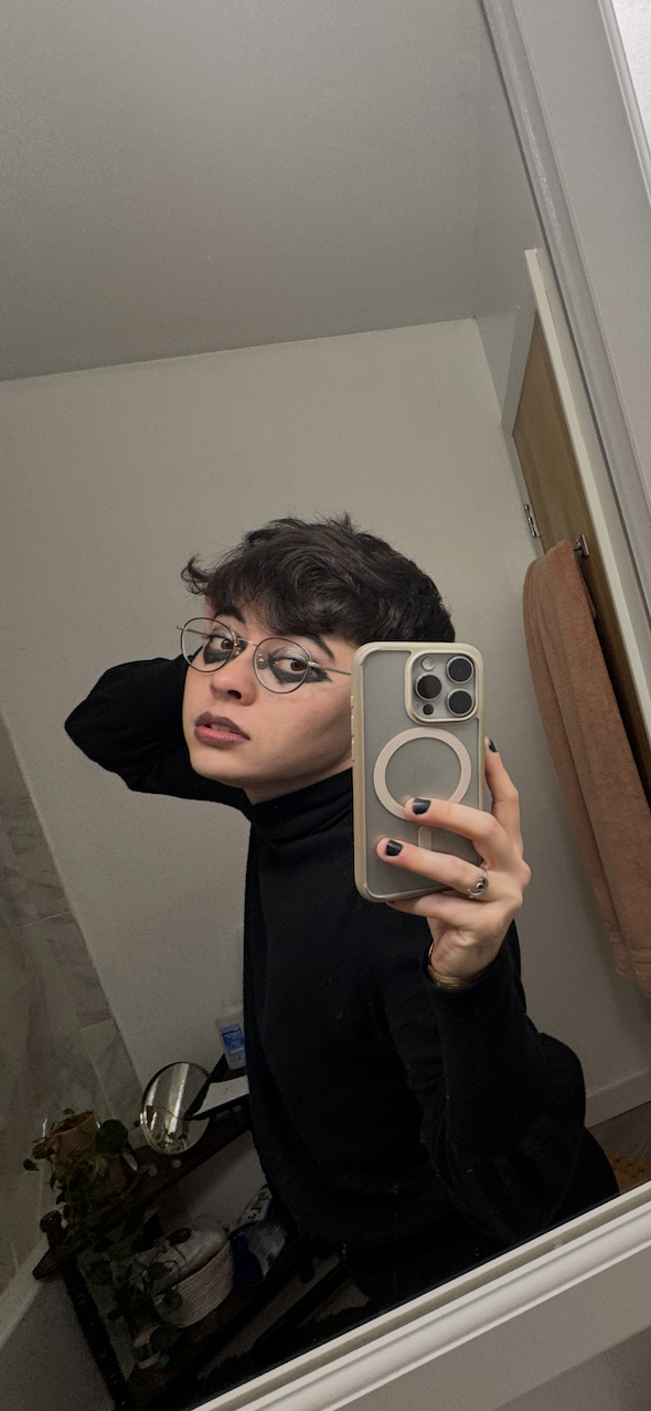 A bathroom selfie of myself wearing black eyeshadow and lipstick.