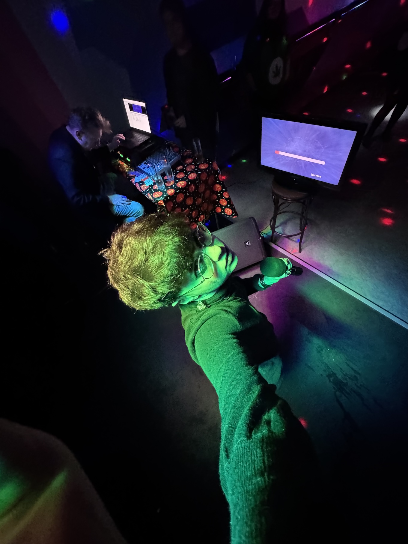 Me taking a dramatic, low-light selfie on stage before a karaoke performance.