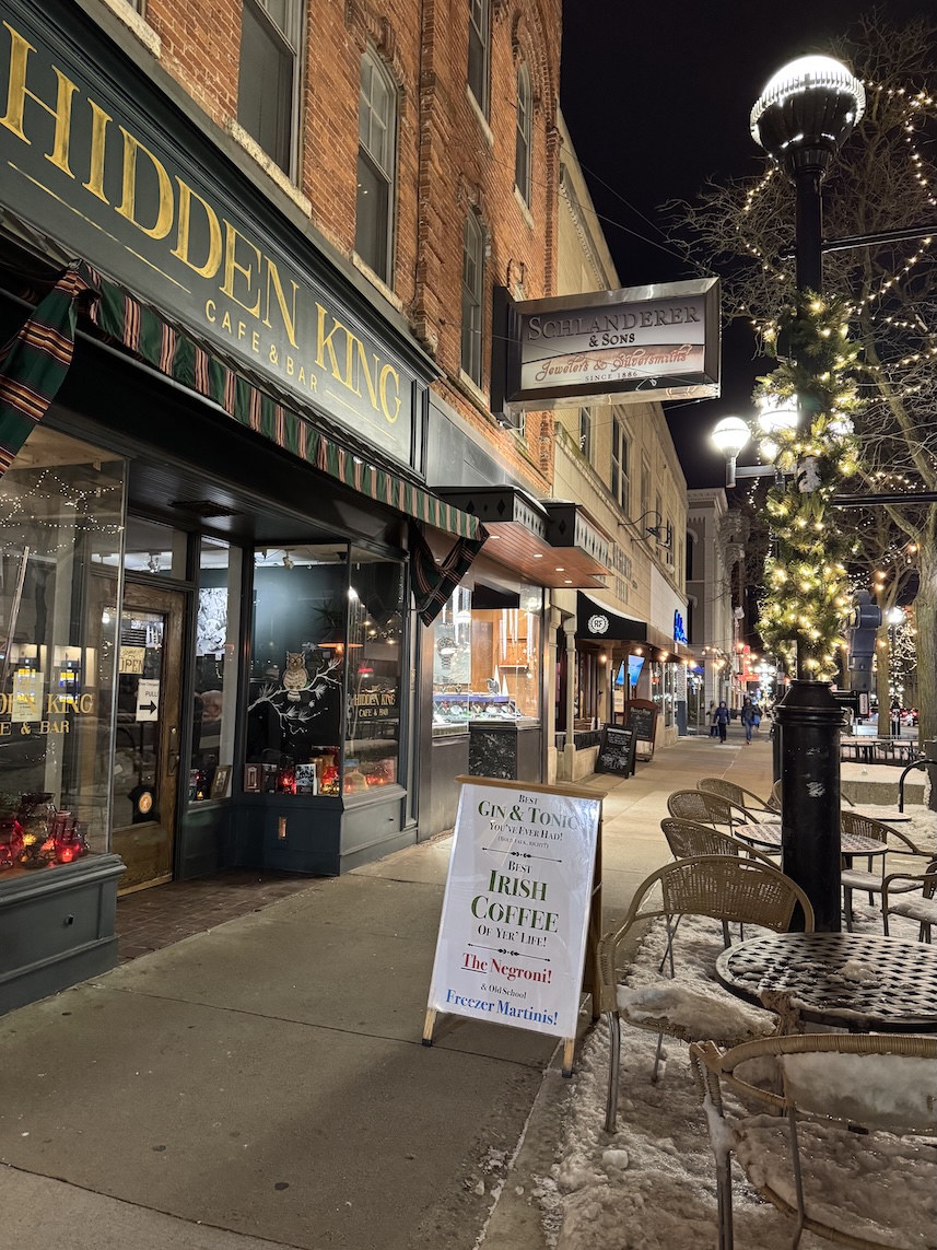 Hidden King Cafe & Bar in downtown Ann Arbor; lots of snow on the ground by the outdoor seats, and Christmas lights wrapped around the streetlamp.