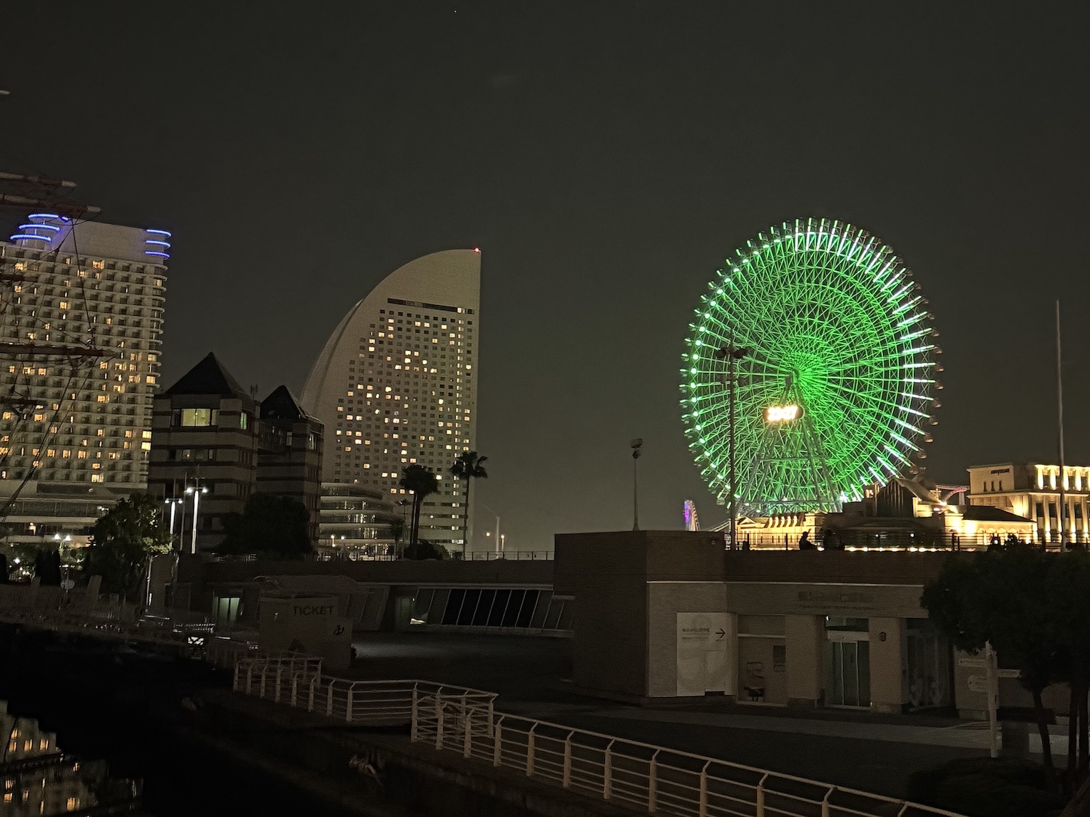 A night photo of a gigantic green ferris wheel by the portside in Yokohama, Japan